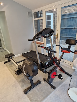 Ett hemmagym med löpband, motionscykel och en viktbänk.