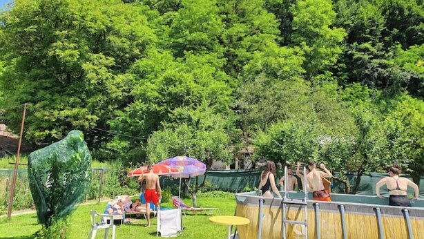 Un espace piscine doté d’une terrasse en bois, de chaises longues et de parasols.