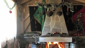Une cheminée en pierre avec un feu allumé, entourée de décorations de Noël et d’un sapin de Noël.