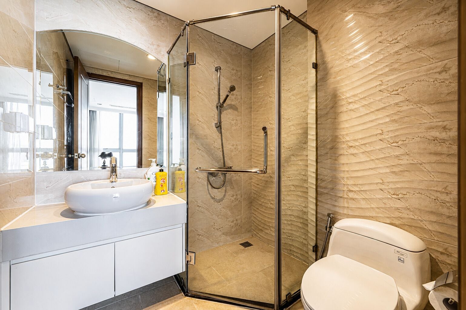 A modern bathroom with a glass-enclosed shower, a white sink, and a toilet.
