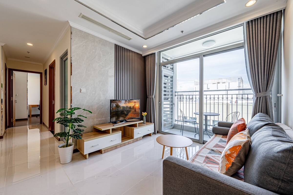 A modern living room with a flat-screen TV, a sofa, a coffee table, and a potted plant.