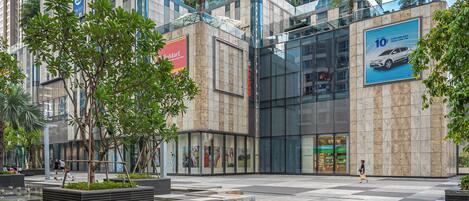 A modern urban plaza with a large glass building, a McDonald's sign, and a car advertisement.