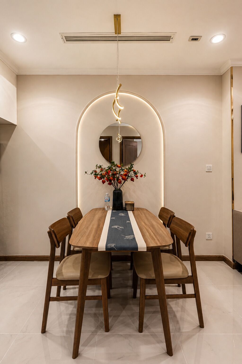 A dining area with a round table, six chairs, a vase with flowers, and a modern pendant light.