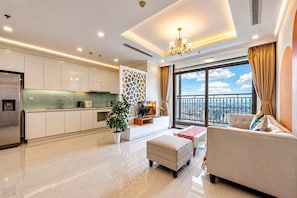 Un salon moderne comprenant un canapé, un pouf et un coin repas avec une table et des chaises.