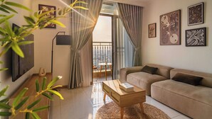 A modern living room with a sofa, a coffee table, and a TV on the wall. - Vinhomes Central Park Premier Apartment (Ho Chi Minh City)