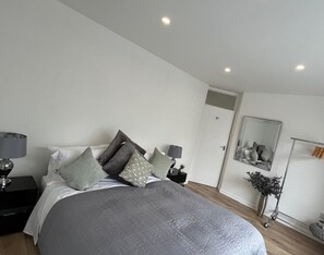 Relax in this serene bedroom with a large bed, bedside tables, and a spacious mirror.
