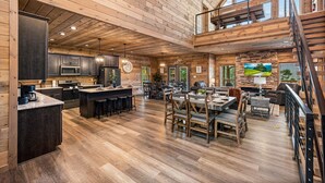 A spacious open-plan living area with a kitchen, dining area, and a loft bedroom. - Mountain Views ~5-King BD~Gameroom~HotTub~Firepit (Sevierville)