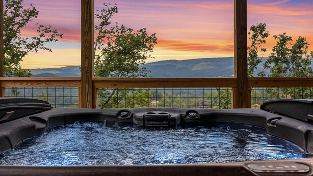 A hot tub with a view of mountains and a sunset through large windows. - Mountain Views ~5-King BD~Gameroom~HotTub~Firepit (Sevierville)