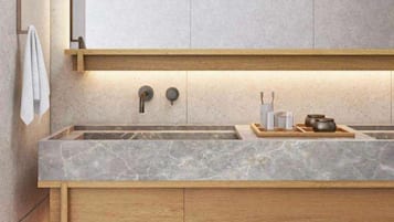Un baño moderno con lavamanos de mármol, tocador de madera y un perchero para toallas.