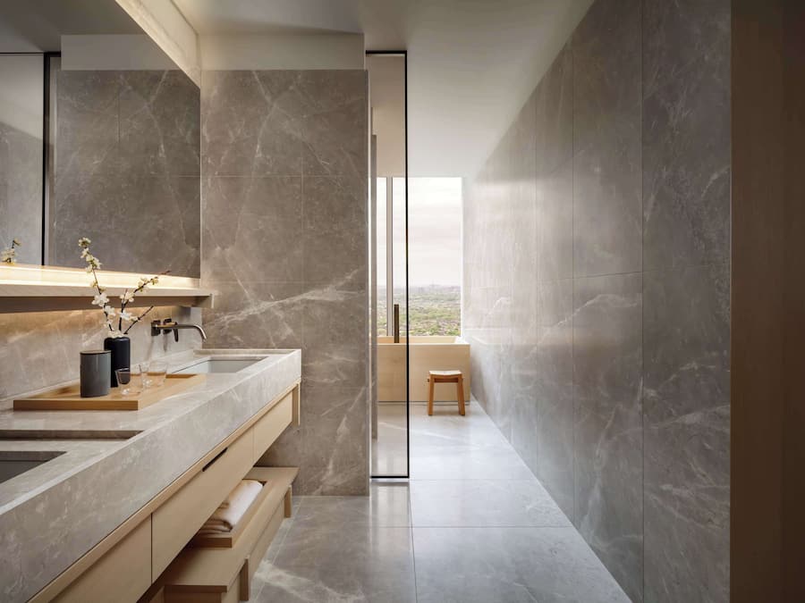 A modern bathroom with a large mirror, two sinks, and a view of the outdoors.
