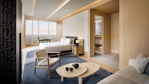 Habitación de hotel moderna con una cama grande, un área de descanso con una mesa y vistas a la ciudad.