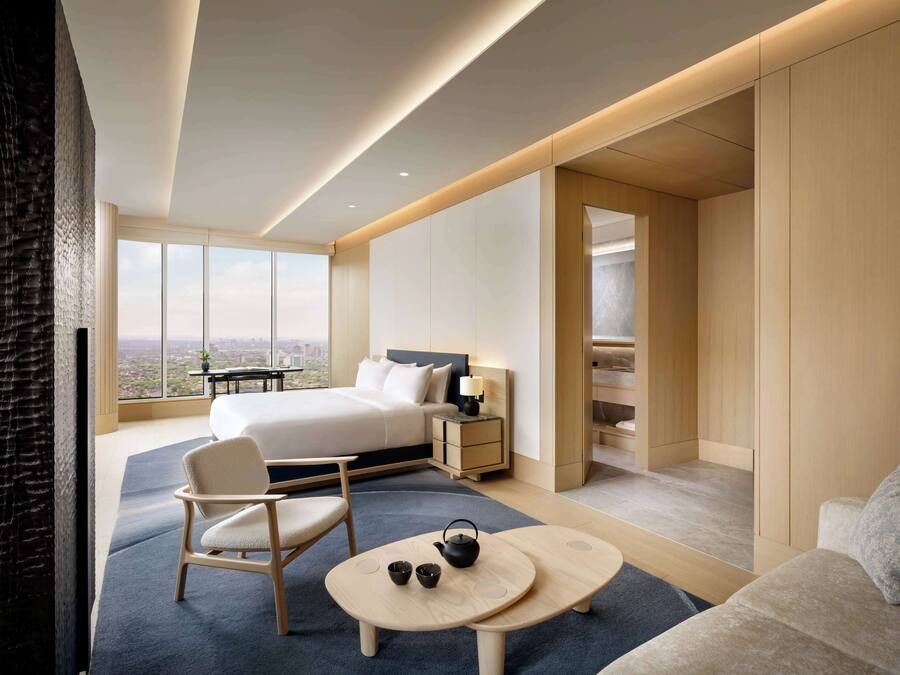 Een moderne hotelkamer met een groot bed, een zithoek met een tafel en uitzicht op de stad.