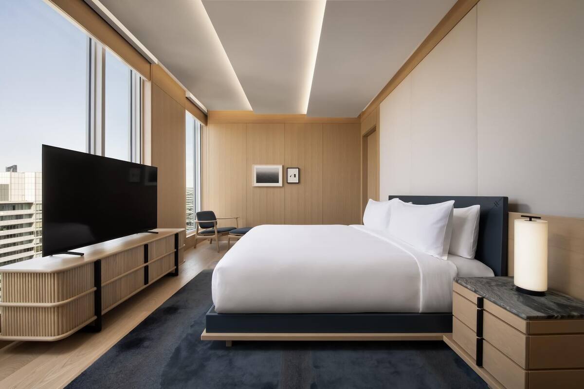 Et moderne hotelværelse med en stor seng, et fladskærms-tv, et skrivebord og en stol.