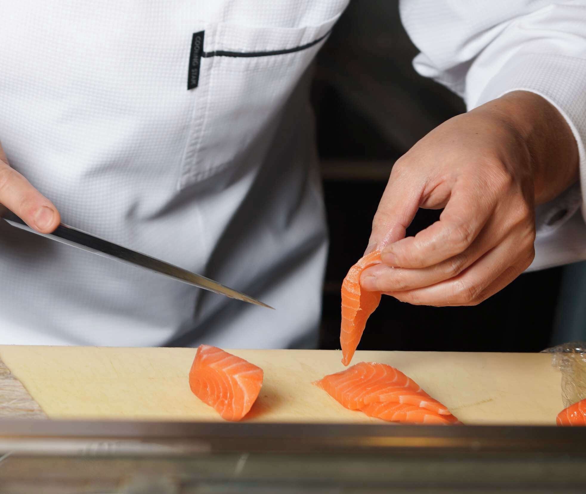 Iemand snijdt zalm op een snijplank.