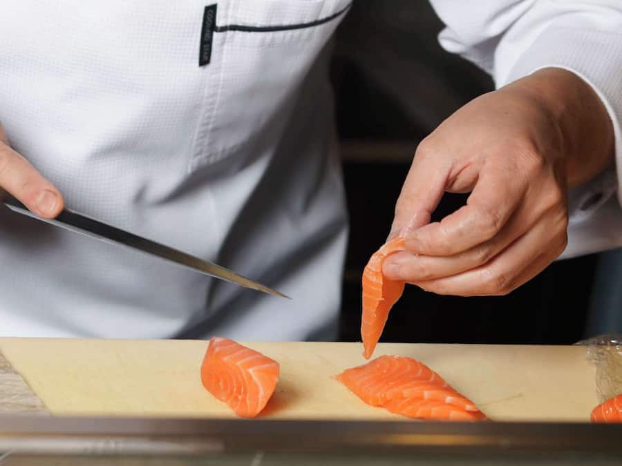 A person slicing salmon on a cutting board.