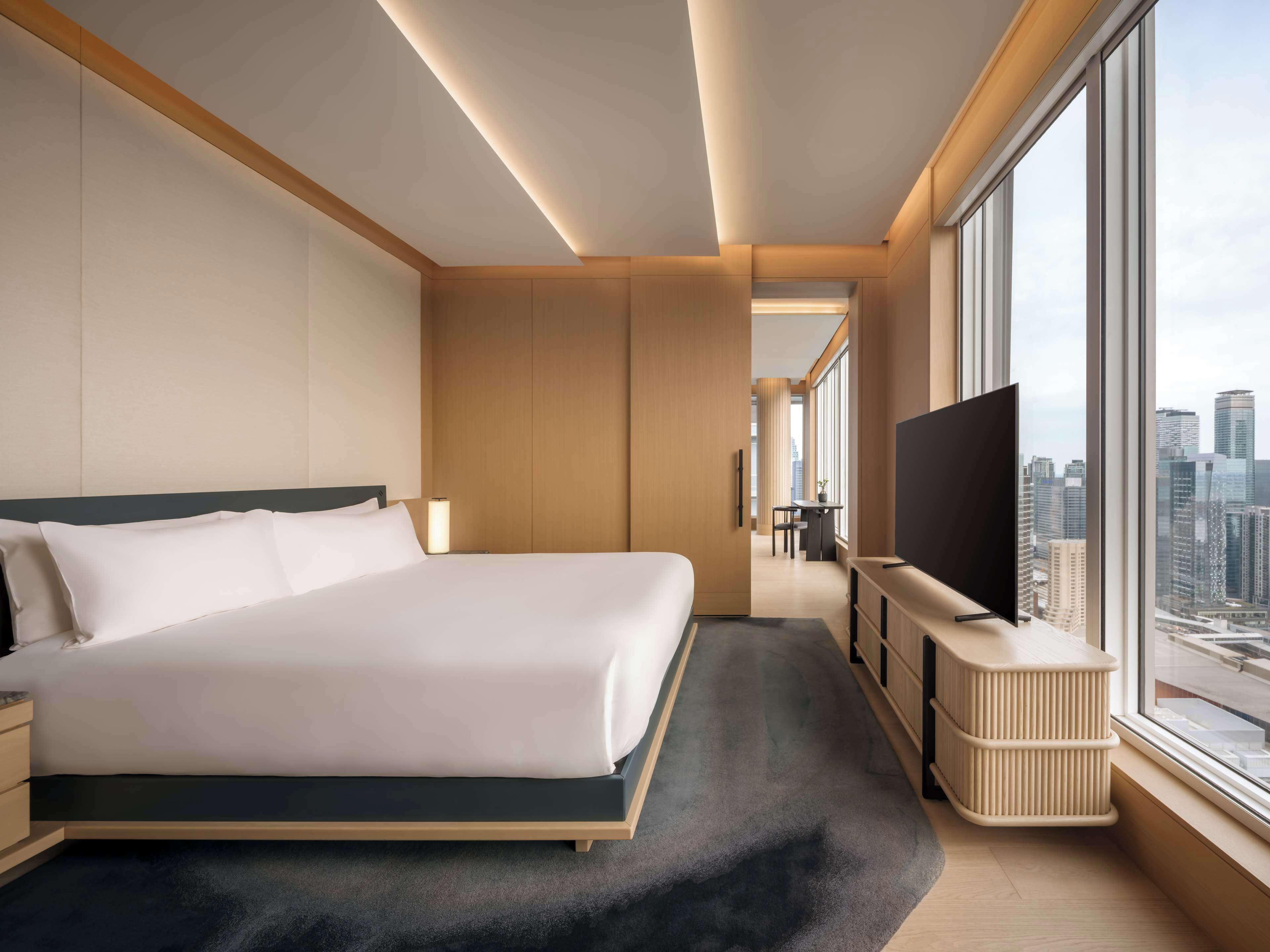 Une chambre d’hôtel moderne avec un grand lit, une télévision et une vue sur la ville.