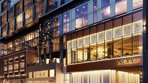 A modern hotel with a prominent glass facade, a spacious entrance, and a visible name "NOBU".