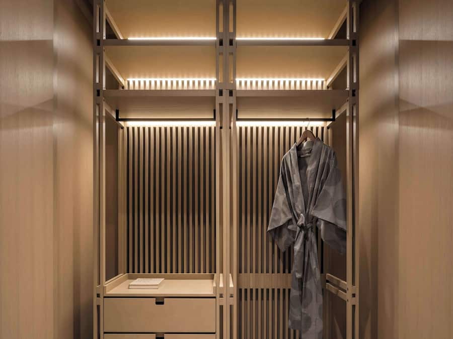 A modern, minimalist walk-in closet with built-in drawers and a shoe rack.