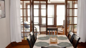A dining room with a table set for six, wooden chairs, a chandelier, and a view through a glass door to a balcony. - Wild Rose Cottage



Save
 (De Smet)
