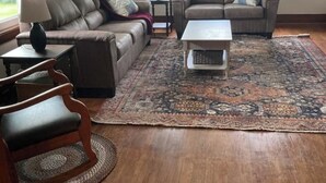 A living room with a brown leather sofa, a matching armchair, a coffee table, and a patterned rug. - Wild Rose Cottage



Save
 (De Smet)