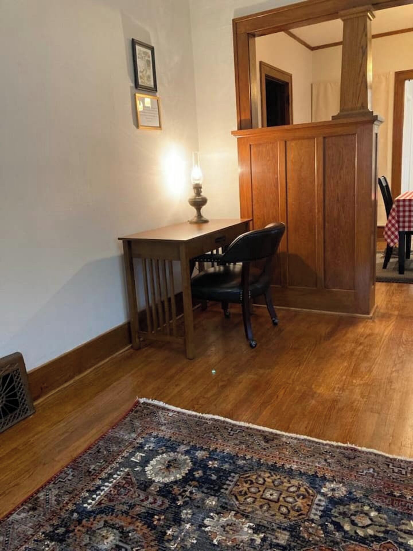 Een kamer met een houten bureau, een stoel, een kamerbreed tapijt met een patroon en een houten scheidingswand.