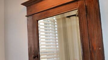 A wooden medicine cabinet with a mirror, a towel rack, and a light fixture above it.