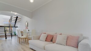 A modern living room with a sofa, chairs, a dining table, and a staircase. - Villa Quinta Grande (Camara de Lobos)