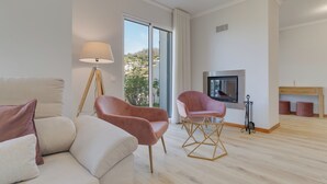 A modern living room with a sofa, two armchairs, a floor lamp, a TV, and a fireplace. - Villa Quinta Grande (Camara de Lobos)