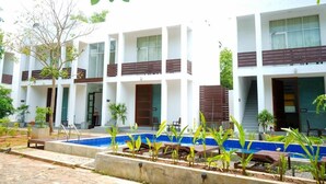 A modern building with multiple balconies, a swimming pool, and a garden area. - Ananthara Resort (Anuradhapura)