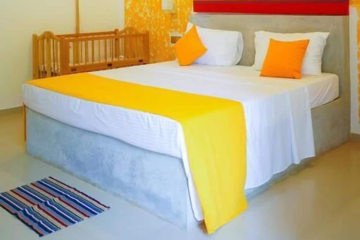 A bedroom with a bed, a ceiling fan, a bedside table, and a wall with a textured pattern.
