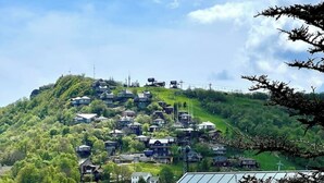 Rinteenpuoleinen asuinalue, jossa on taloja, tie ja rakennus, jonka katolla on aurinkopaneeli.