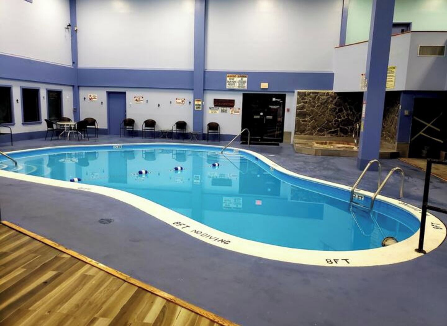 An indoor swimming pool with a wooden deck surrounding it.