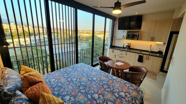 Ein Schlafzimmer mit einem großen Bett, einem Balkon mit Blick auf die Stadt und einer Küchenzeile.