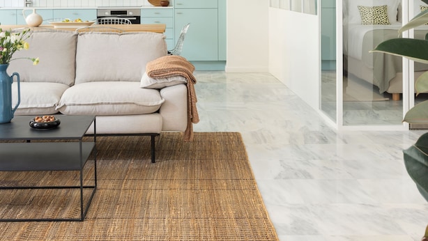 A modern living room with a sofa, coffee table, and a large window. - Silk n Cotton (Athens)