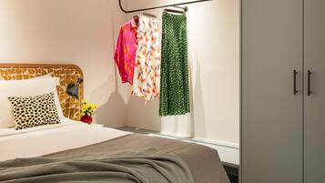 A neatly made bed with a patterned headboard, a bedside lamp, and a vase with flowers.
