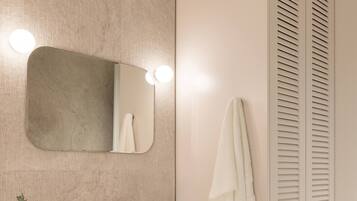 Un baño moderno con lavabo blanco, espejo y lavadora integrada.