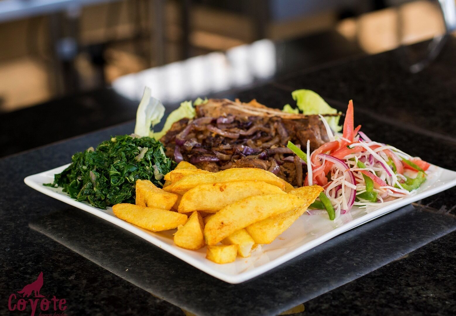 A plate of food with fries, greens, and a meat dish.