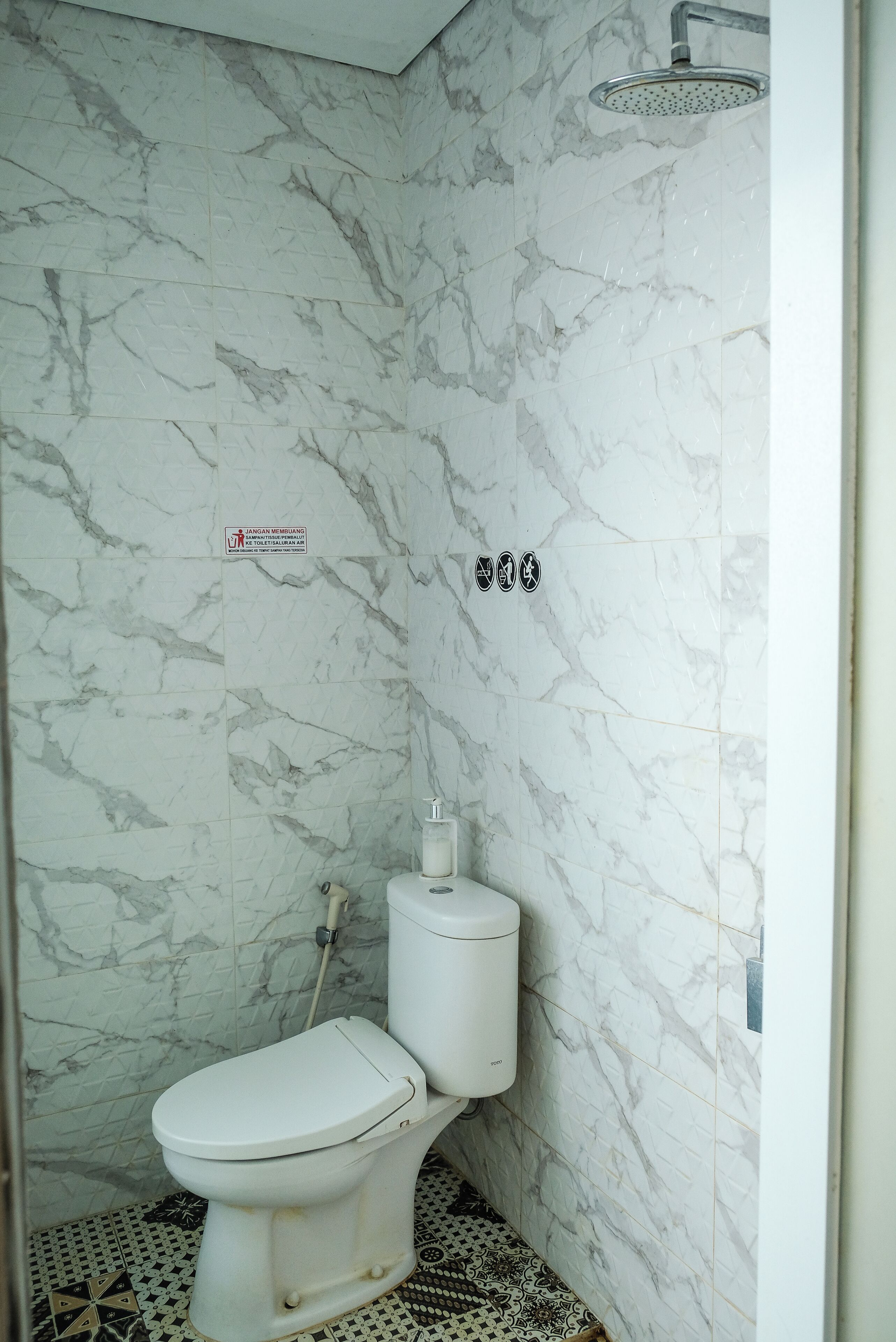 A bathroom with a toilet, a shower, and a marble wall.