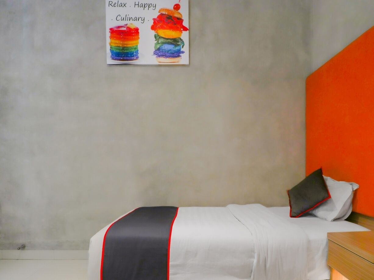 A bedroom with a bed, a nightstand, and a wall-mounted picture.