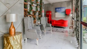 A modern lobby with checkered chairs, a red telephone booth, and a 'RELAX TIME' sign. - The Batik Bed and Coffee (Bandung)