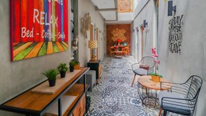 A narrow hallway with a colorful wall mural, a small seating area with a table and chairs, and a patterned floor. - The Batik Bed and Coffee (Bandung)