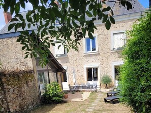 Edificio de piedra con un patio, asientos exteriores y un pequeño jardín.