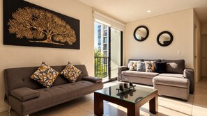 A living room with two sofas, a coffee table, and a large gold tree artwork on the wall.