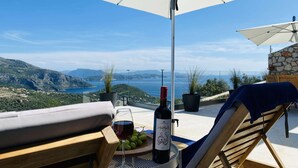 Eine Terrasse mit Tisch, Stühlen und einer Weinflasche, mit Blick auf eine schöne Landschaft.