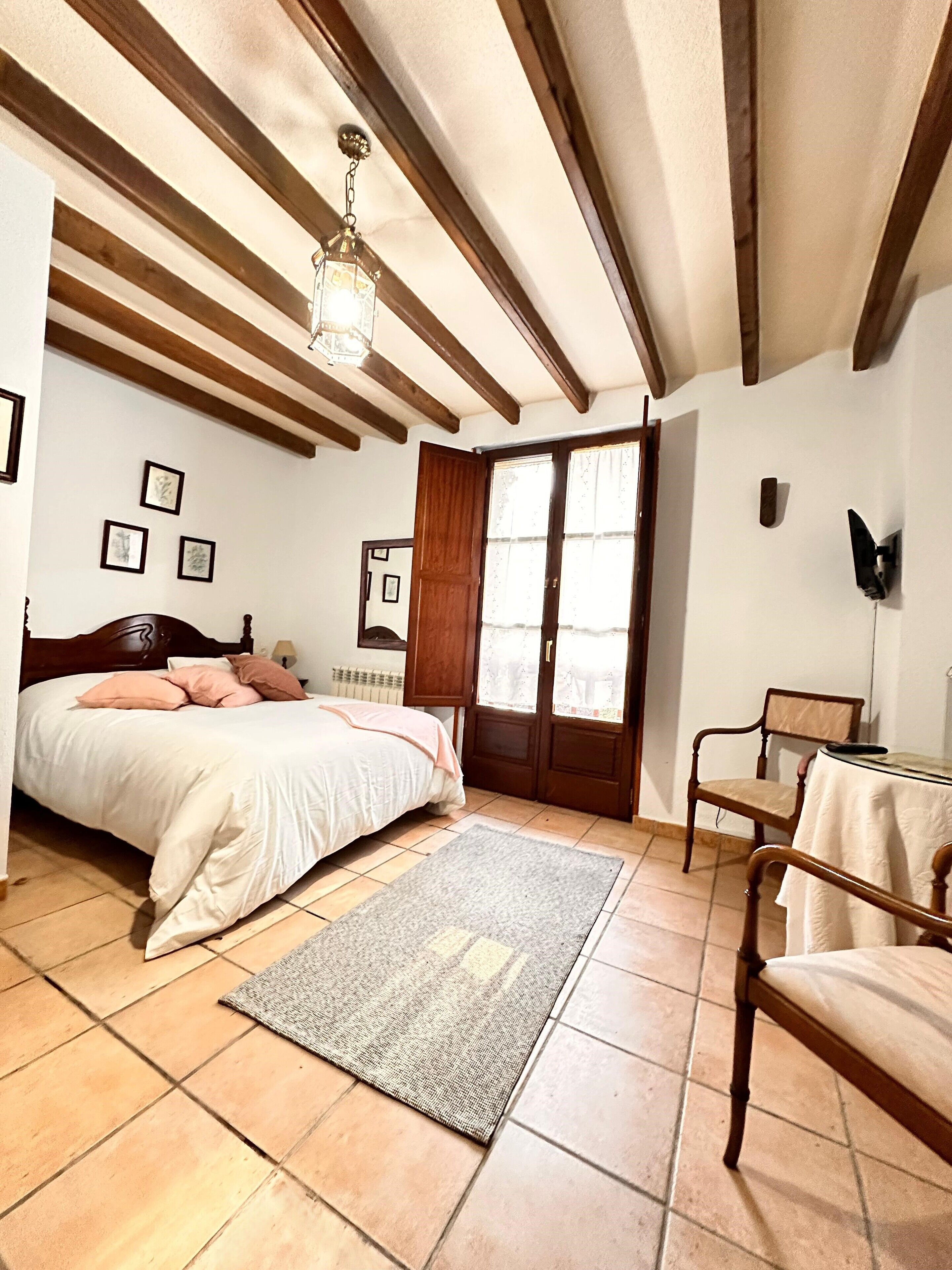 A bedroom with a bed, a chair, a rug, and a ceiling fan.