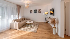 A modern living room with a sectional sofa, a round coffee table, and a decorative floor lamp. - Fantastic apartment - Terrace- Hanging chair- Highspeed WiFi (Viersen)
