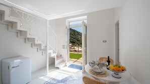 A modern kitchen with a built-in refrigerator, a dining area with a table set for two, and a staircase leading to an outdoor patio. - YourHome - Casa Lucente (Positano)