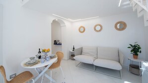 A modern, white interior with a dining area, sofa, and decorative wall elements. - YourHome - Casa Lucente (Positano)