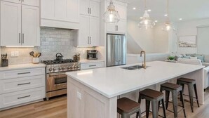 Una cocina moderna con armarios blancos, electrodomésticos de acero inoxidable y una isla grande con taburetes de bar.