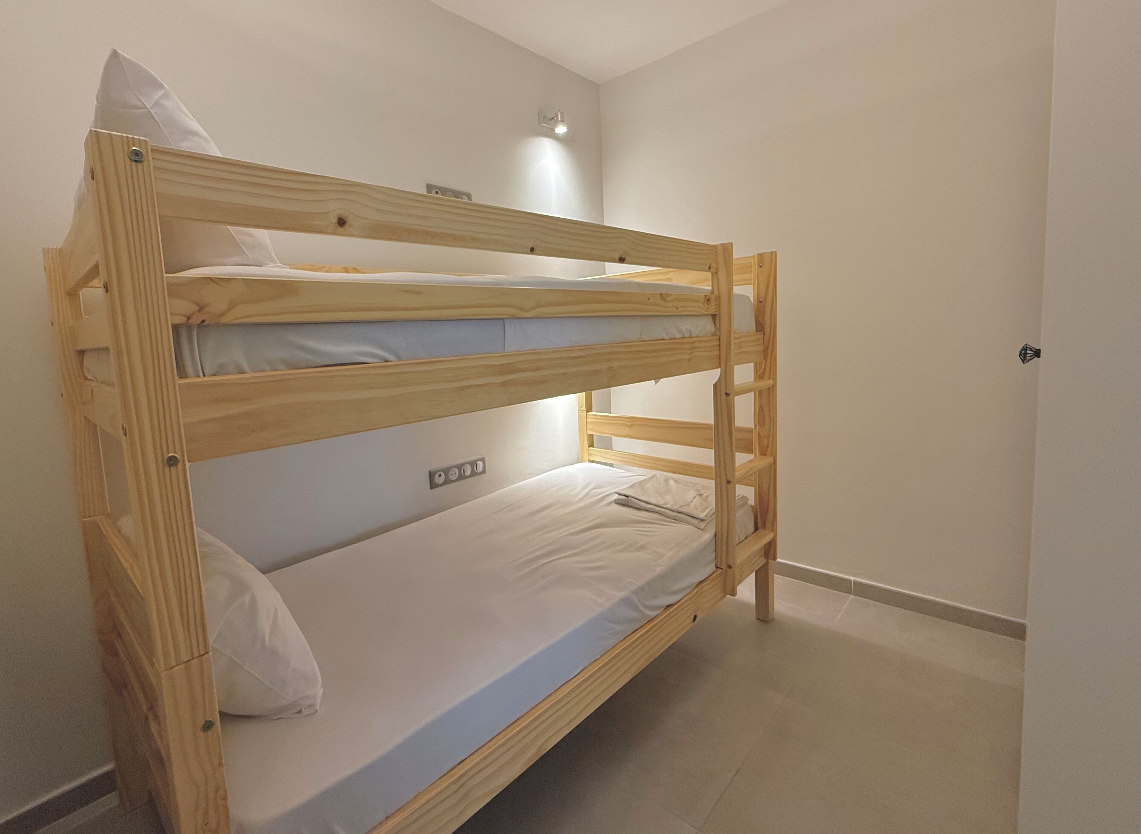 A bunk bed with a wooden frame and white bedding.